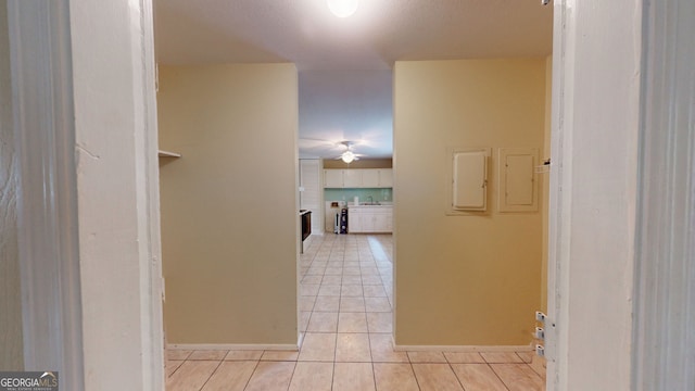 corridor featuring light tile patterned floors and baseboards
