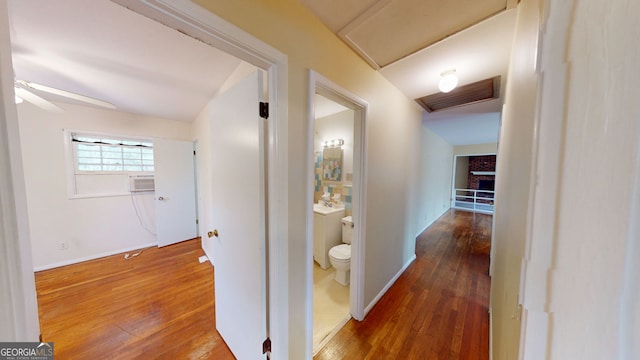 hall with baseboards, visible vents, attic access, and hardwood / wood-style floors