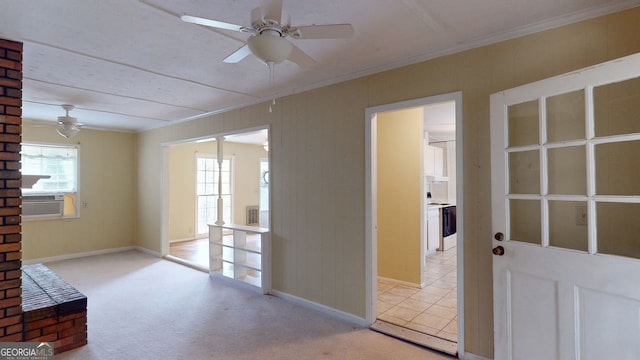 interior space with baseboards, ceiling fan, ornamental molding, and light colored carpet