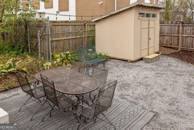 exterior space with an outdoor structure, a shed, a patio, a fenced backyard, and outdoor dining area