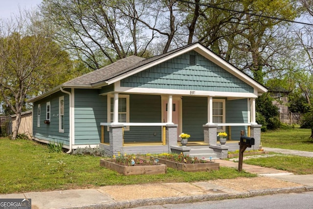 bungalow-style house with a garden, covered porch, and a front yard