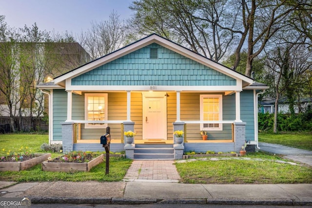 bungalow with a front lawn, a porch, and a vegetable garden