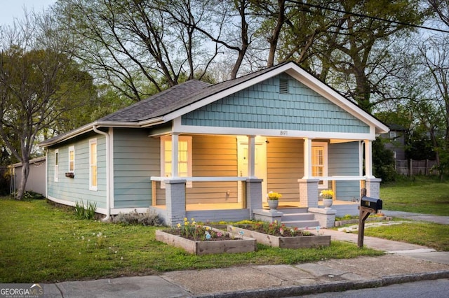 bungalow-style house featuring a garden, a porch, and a front lawn