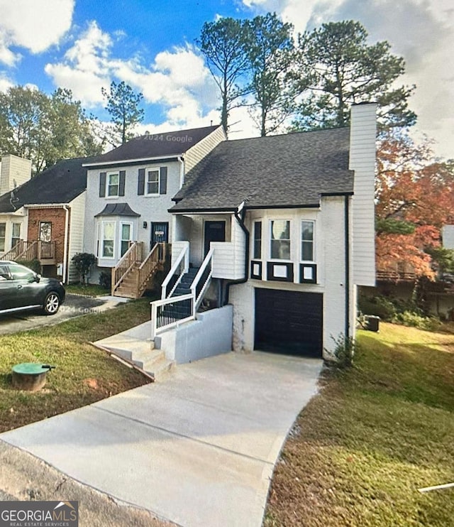 view of front of property with stairs, driveway, a chimney, a front lawn, and a garage