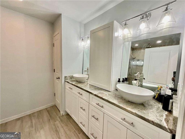 bathroom with double vanity, a sink, a stall shower, and wood finished floors