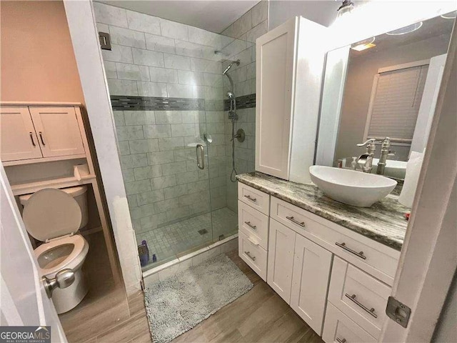 bathroom featuring wood finished floors, vanity, toilet, and a shower stall