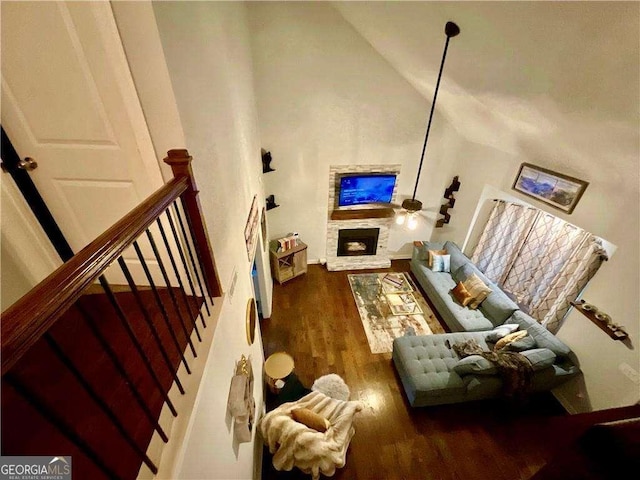 living area featuring high vaulted ceiling, a fireplace, wood finished floors, and stairs