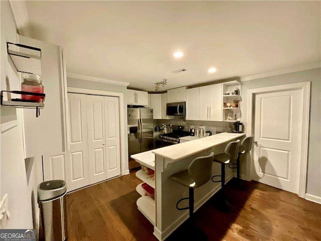 kitchen with dark wood-style flooring, crown molding, stainless steel appliances, white cabinetry, and open shelves