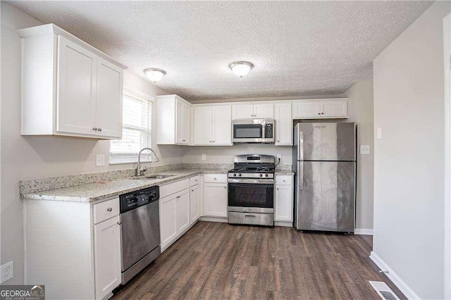 kitchen with visible vents, white cabinetry, a sink, and stainless steel appliances