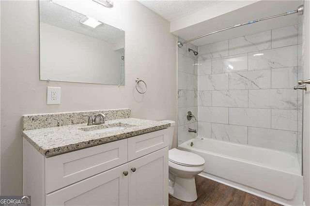 bathroom featuring toilet, vanity, wood finished floors, washtub / shower combination, and a textured ceiling