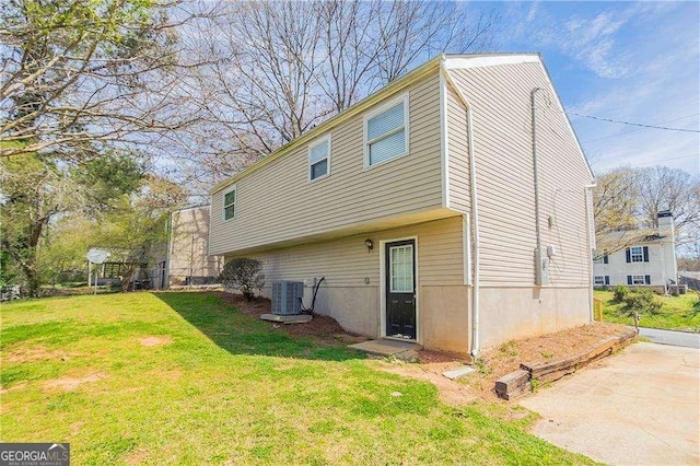 rear view of house with cooling unit and a yard