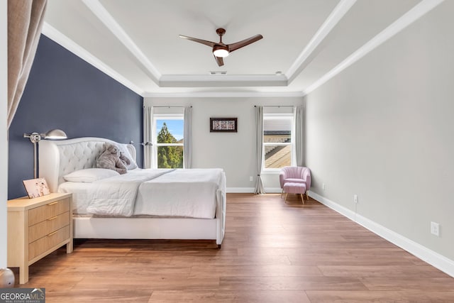 bedroom featuring ceiling fan, a raised ceiling, light wood-style flooring, baseboards, and visible vents