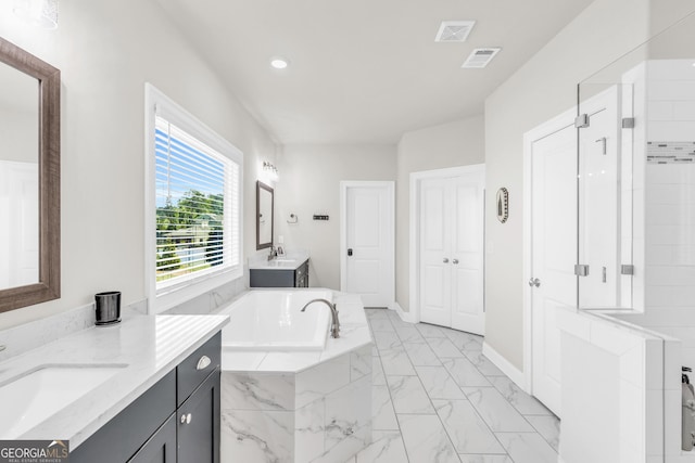 full bathroom featuring visible vents, a garden tub, marble finish floor, two vanities, and a sink