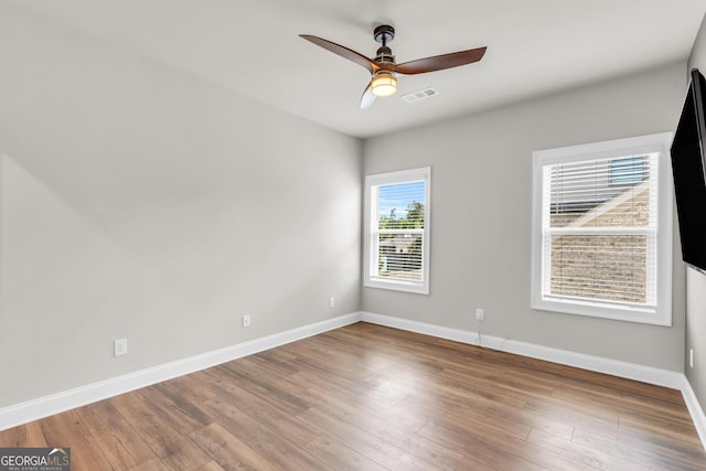 empty room featuring visible vents, baseboards, ceiling fan, and wood finished floors
