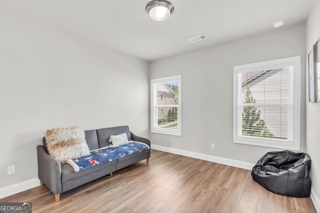 living area featuring baseboards, visible vents, and wood finished floors