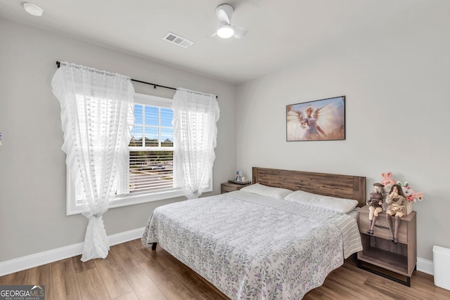 bedroom with baseboards, wood finished floors, and visible vents