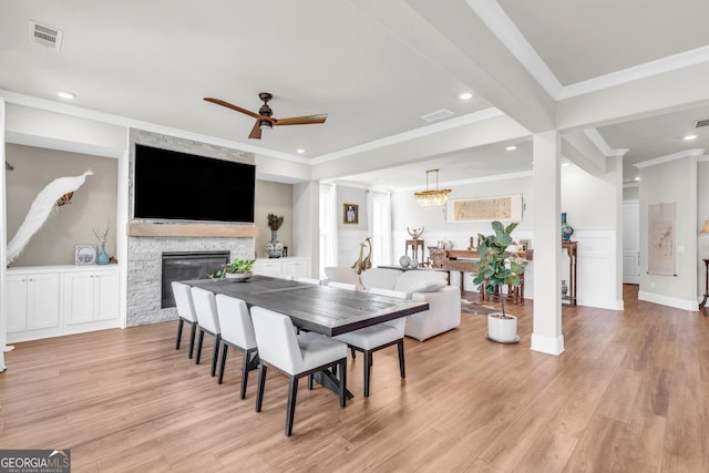 dining room featuring ornamental molding, ceiling fan with notable chandelier, light wood-style flooring, and visible vents