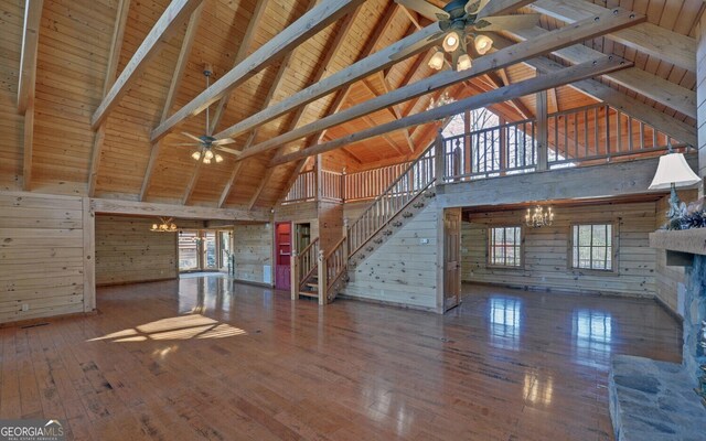 221 Laurel Cir, Dahlonega, GA 30533 - unfurnished living room featuring stairs, hardwood / wood-style floors, a fireplace with raised hearth, ceiling fan with notable chandelier, and wooden walls