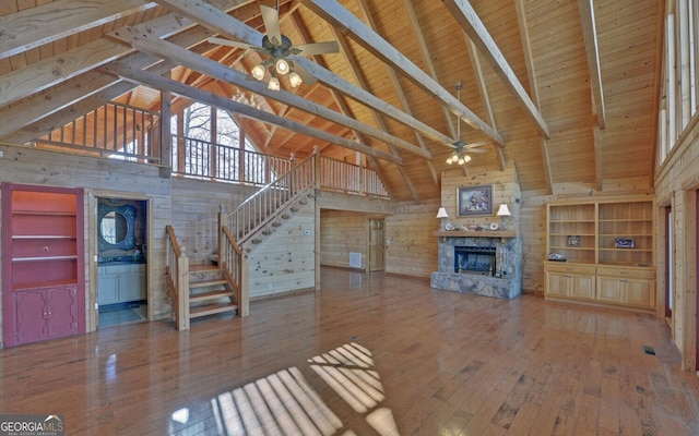221 Laurel Cir, Dahlonega, GA 30533 - unfurnished living room with hardwood / wood-style floors, a stone fireplace, wood walls, and a ceiling fan