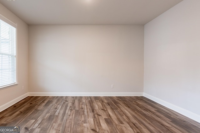 unfurnished room featuring wood finished floors, plenty of natural light, and baseboards