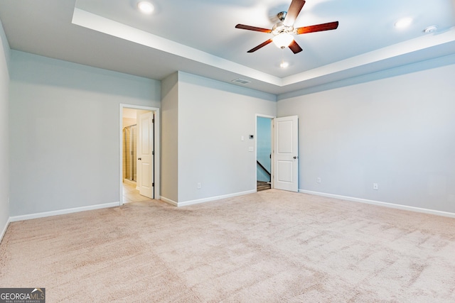 unfurnished room with a tray ceiling, ceiling fan, baseboards, light carpet, and recessed lighting