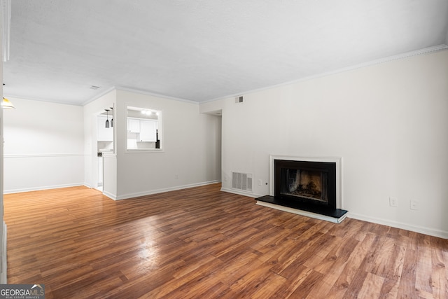 unfurnished living room featuring wood finished floors, a fireplace with raised hearth, baseboards, and visible vents