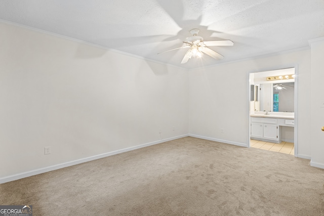 unfurnished bedroom with baseboards, light carpet, ensuite bath, a textured ceiling, and crown molding