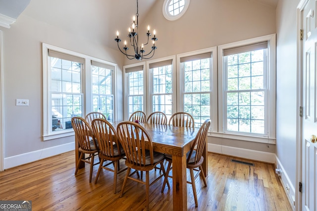 dining space with light wood finished floors, baseboards, lofted ceiling, and a chandelier