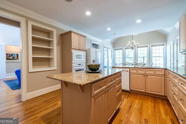 kitchen featuring white appliances, a chandelier, a kitchen island, light wood finished floors, and a peninsula