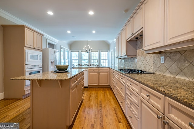 kitchen with a peninsula, white appliances, tasteful backsplash, light wood-style floors, and a notable chandelier