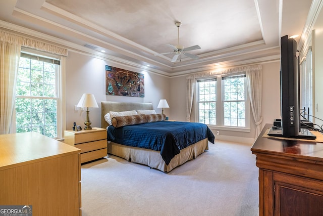 bedroom with a tray ceiling, light colored carpet, and crown molding