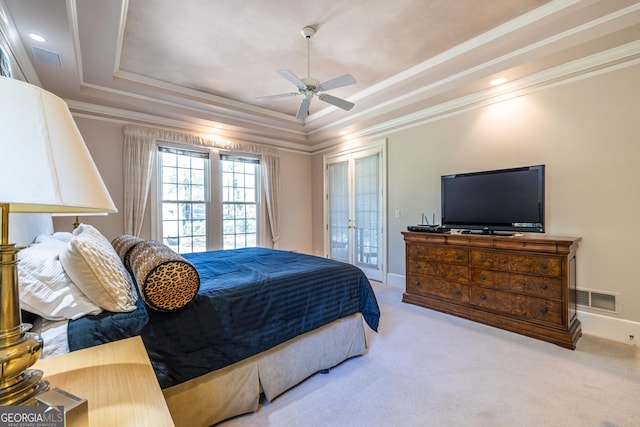 carpeted bedroom with a tray ceiling, visible vents, and crown molding