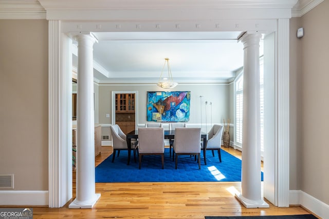 dining area with wood finished floors and ornate columns