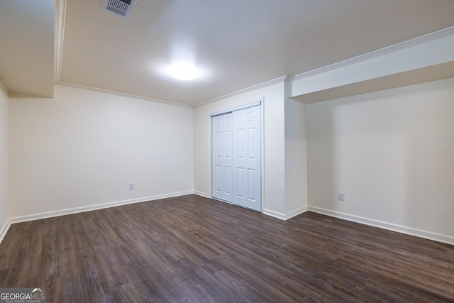 below grade area with dark wood-style floors, visible vents, baseboards, and ornamental molding