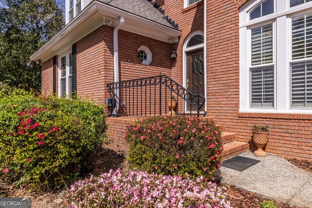 view of property exterior featuring brick siding and roof with shingles