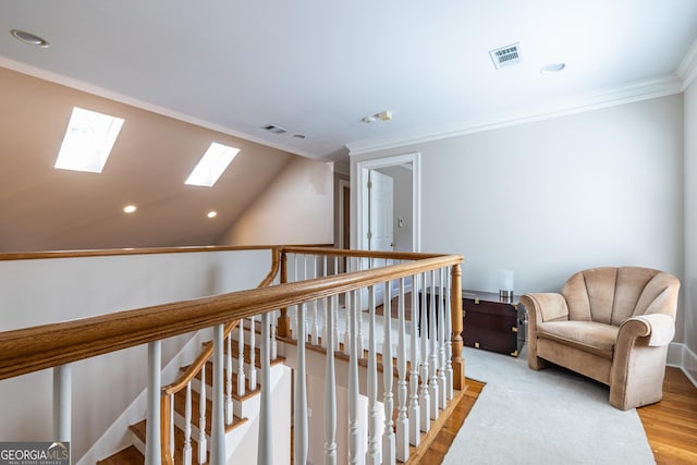 living area with an upstairs landing, light wood-style flooring, visible vents, crown molding, and lofted ceiling with skylight