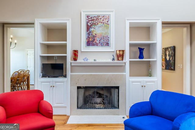 living room with wood finished floors, a fireplace, and built in shelves