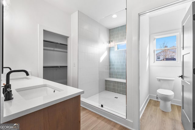 full bathroom featuring a stall shower, wood finished floors, toilet, vanity, and recessed lighting