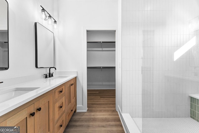 full bath with wood finished floors, walk in shower, double vanity, and a walk in closet