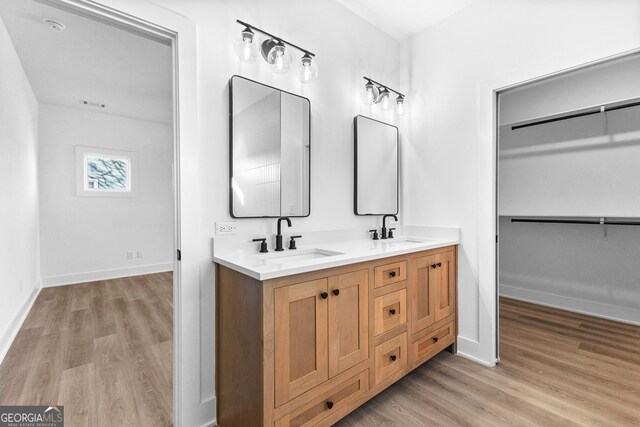 bathroom featuring wood finished floors, double vanity, and baseboards