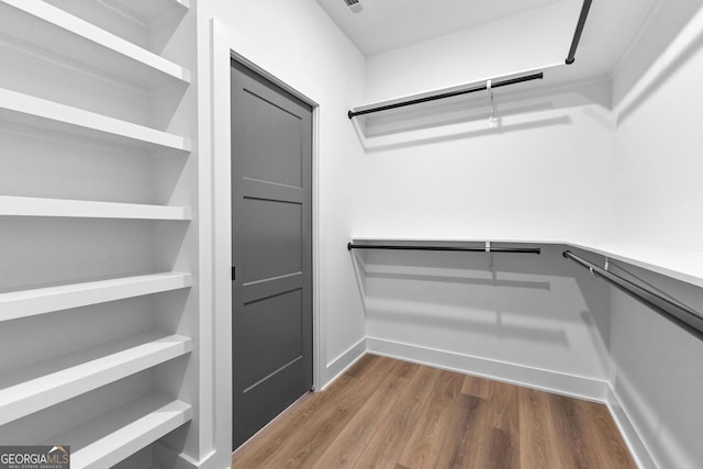 walk in closet with wood finished floors
