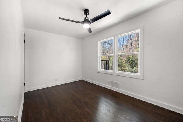 empty room featuring baseboards, dark wood-style floors, visible vents, and a ceiling fan
