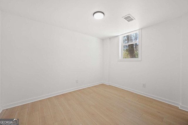 unfurnished room featuring baseboards, visible vents, and light wood-style floors