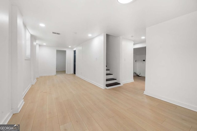 empty room featuring stairway, light wood-style flooring, baseboards, visible vents, and recessed lighting