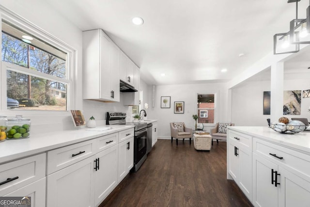 kitchen featuring dark wood-type flooring, under cabinet range hood, white cabinetry, and stainless steel electric range