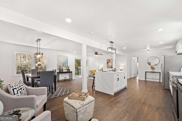 living room with plenty of natural light, dark wood-type flooring, and ceiling fan