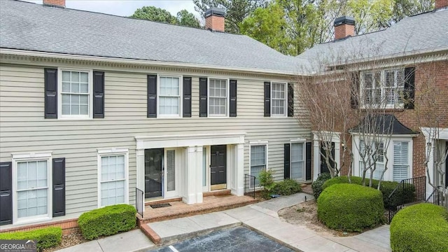 view of front of home featuring a chimney and roof with shingles