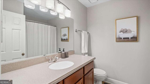 bathroom with baseboards, toilet, a shower with shower curtain, and vanity