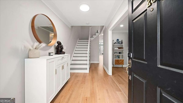 foyer with baseboards, stairway, light wood finished floors, and crown molding