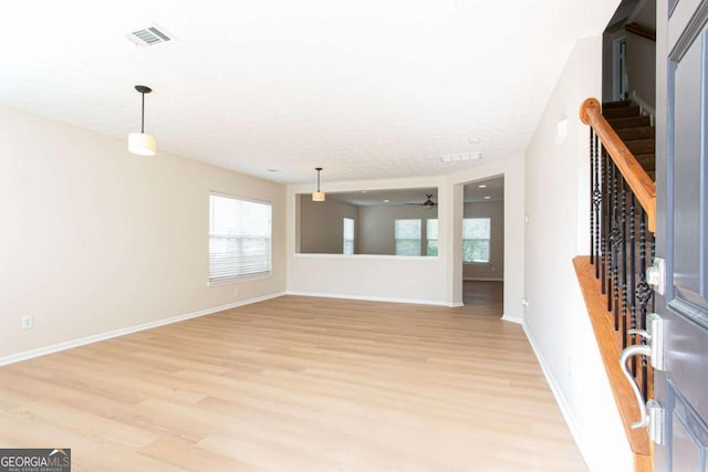 1924 Sweet Flag Rd, Lawrenceville, GA 30045 - unfurnished living room featuring light wood finished floors, stairs, healthy amount of natural light, and a ceiling fan